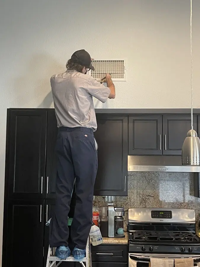 Technician inspecting an air vent during HVAC service in Raleigh Hills